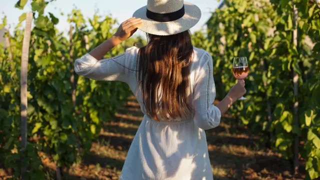 Portrait of a gorgeous brunette woman having wine fun in the vineyards.