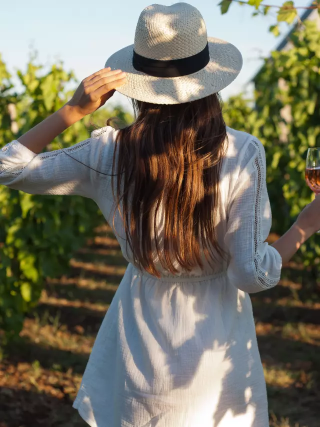 Portrait of a gorgeous brunette woman having wine fun in the vineyards.