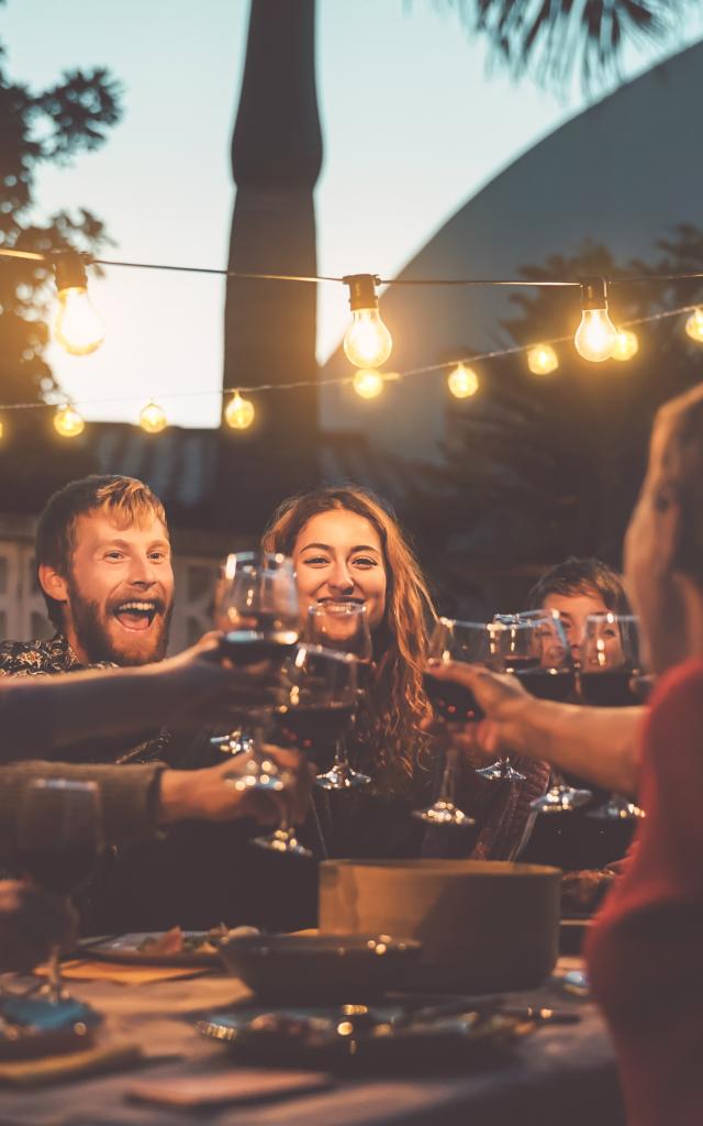 Happy family dining and tasting red wine glasses in barbecue dinner party - People with different ages and ethnicity having fun together - Youth and elderly parents and food weekend activities concept