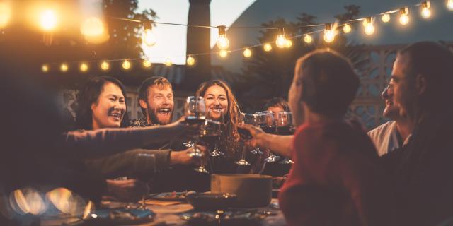 Happy family dining and tasting red wine glasses in barbecue dinner party - People with different ages and ethnicity having fun together - Youth and elderly parents and food weekend activities concept