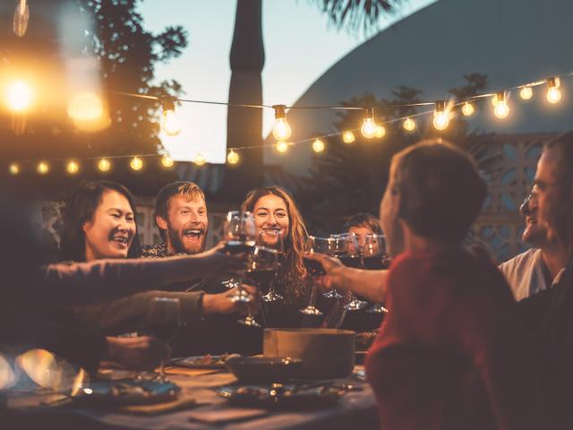 Happy family dining and tasting red wine glasses in barbecue dinner party - People with different ages and ethnicity having fun together - Youth and elderly parents and food weekend activities concept